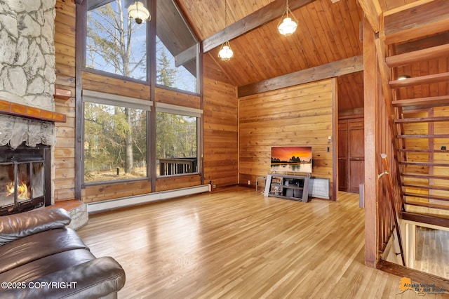 living area with wooden walls, a baseboard heating unit, beam ceiling, a fireplace, and wood finished floors