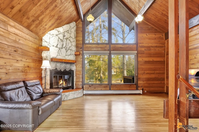 unfurnished living room with a stone fireplace, wood finished floors, wood walls, and baseboard heating