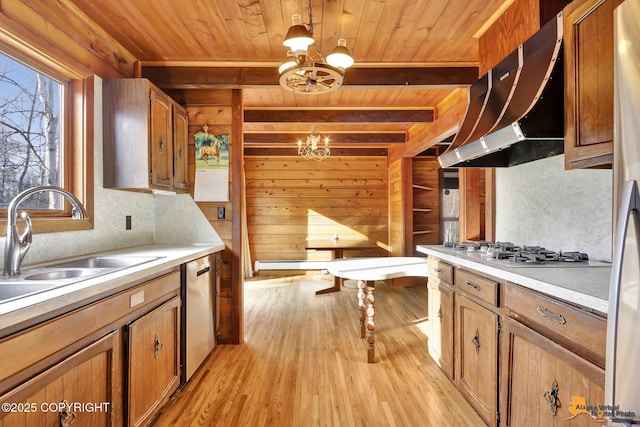 kitchen featuring a sink, an inviting chandelier, wall chimney range hood, white gas cooktop, and dishwasher