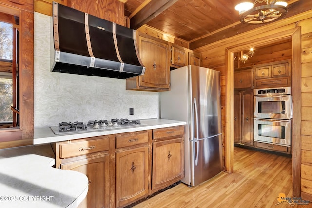 kitchen featuring range hood, light wood-style flooring, light countertops, appliances with stainless steel finishes, and wooden ceiling