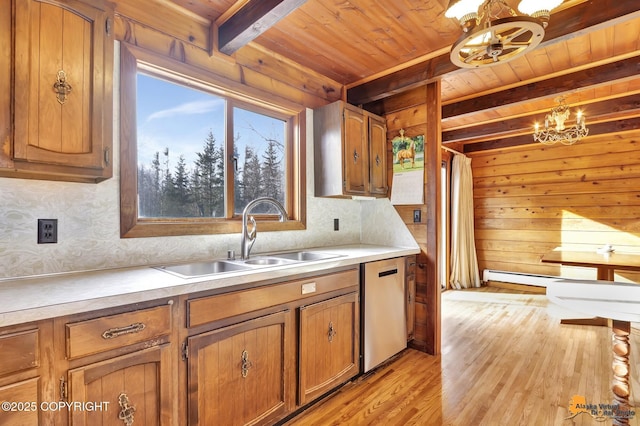 kitchen featuring an inviting chandelier, beam ceiling, a sink, dishwasher, and brown cabinets