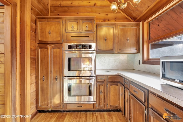 kitchen with light countertops, brown cabinetry, light wood-type flooring, and stainless steel appliances