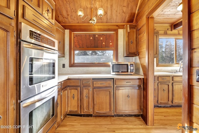 kitchen with wood ceiling, light countertops, light wood-style flooring, brown cabinetry, and stainless steel appliances