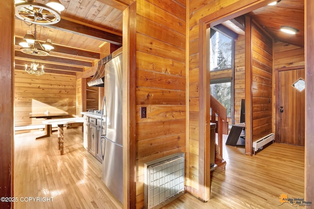 hallway featuring light wood-type flooring, beam ceiling, wooden walls, an inviting chandelier, and wooden ceiling