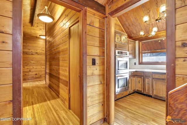 kitchen featuring wooden walls, double oven, light countertops, light wood-style flooring, and wooden ceiling