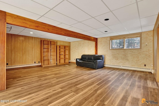 unfurnished room with brick wall, wood finished floors, and a baseboard radiator