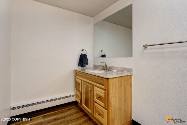 bathroom featuring a baseboard heating unit, wood finished floors, and vanity