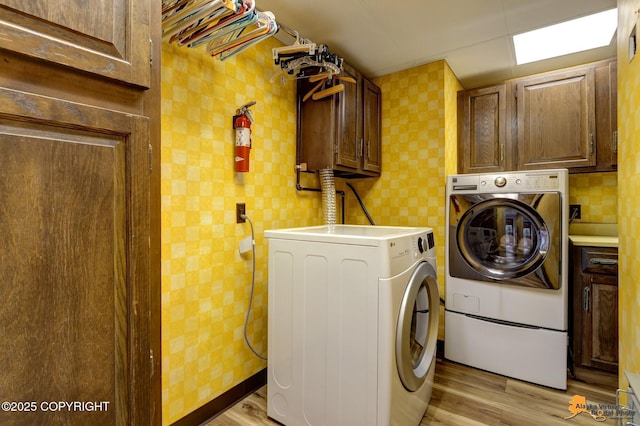 laundry area with light wood finished floors, cabinet space, and wallpapered walls