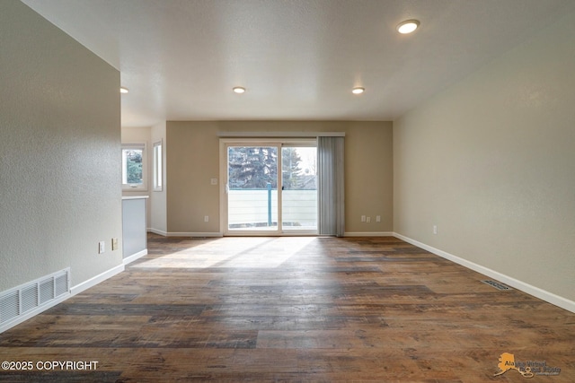 spare room featuring baseboards, wood finished floors, recessed lighting, and a textured wall
