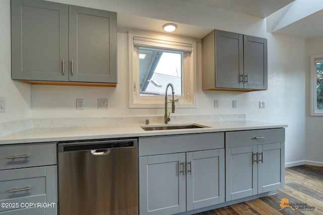 kitchen featuring dishwasher, a sink, and gray cabinetry