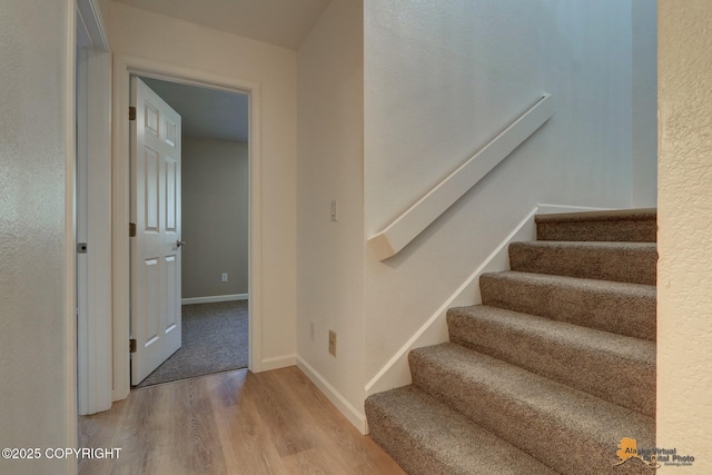 stairway with wood finished floors and baseboards