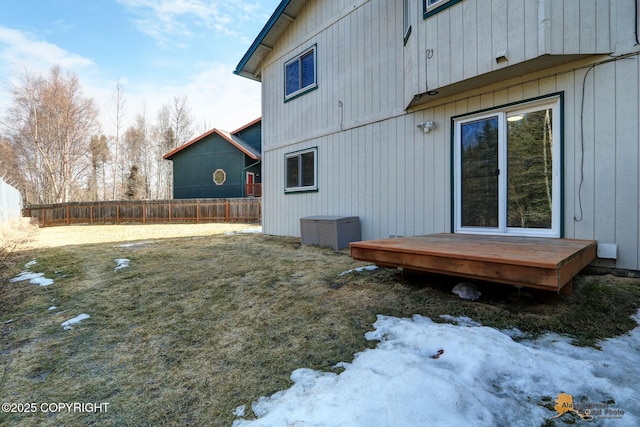 view of snowy exterior with fence, a wooden deck, and cooling unit