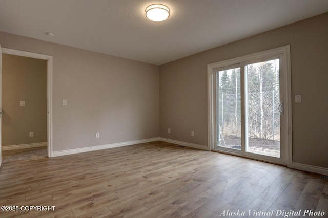 spare room with healthy amount of natural light, wood finished floors, and baseboards