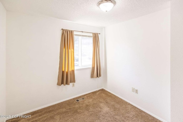 empty room featuring visible vents, baseboards, a textured ceiling, and carpet flooring