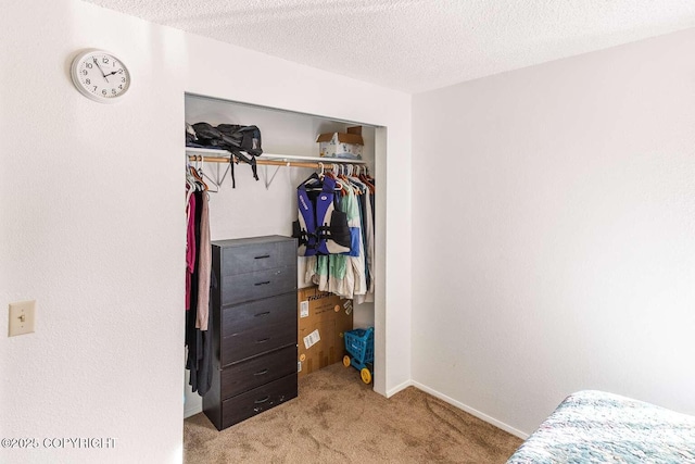 bedroom with a closet, carpet floors, a textured ceiling, and baseboards