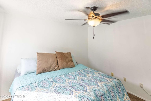 bedroom with a textured ceiling, a ceiling fan, and carpet