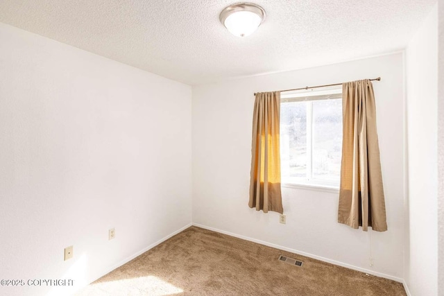 unfurnished room featuring baseboards, visible vents, carpet floors, and a textured ceiling