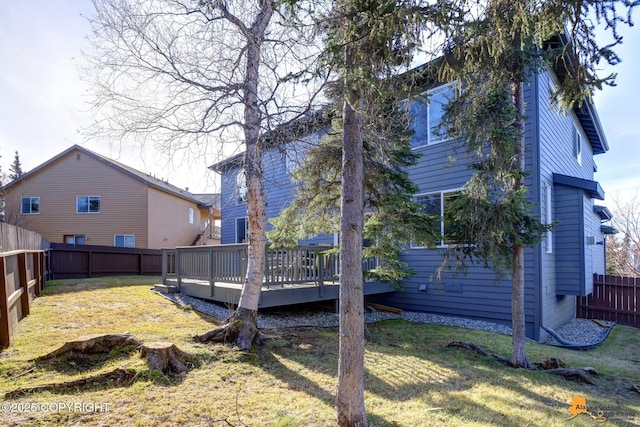 rear view of house featuring a wooden deck, a yard, and a fenced backyard