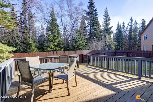 wooden deck with a fenced backyard and outdoor dining space