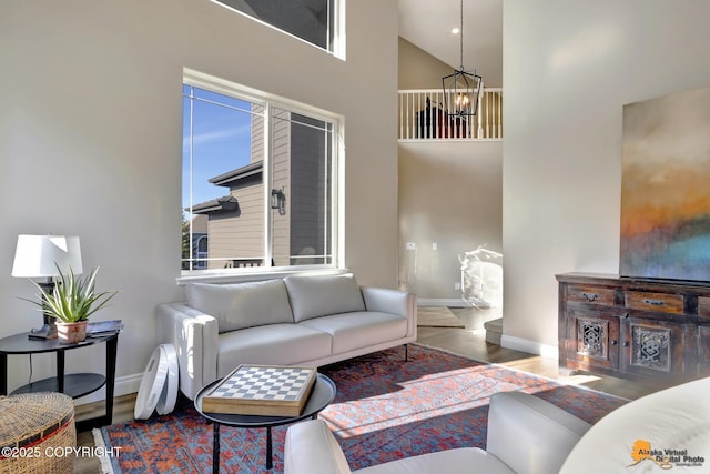 living room featuring a chandelier, baseboards, a towering ceiling, and wood finished floors