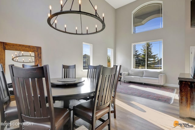 dining space with an inviting chandelier, wood finished floors, and a towering ceiling