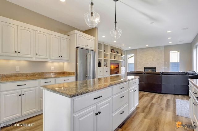 kitchen with light wood-type flooring, a kitchen island, high quality fridge, and a fireplace