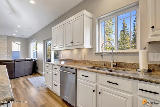 kitchen with light wood-type flooring, a sink, white cabinets, light stone countertops, and dishwasher