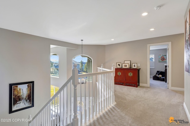 corridor with recessed lighting, baseboards, light carpet, and an upstairs landing