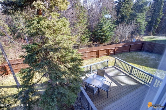 deck featuring a wooded view, a fenced backyard, a lawn, and grilling area