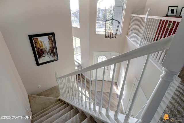 stairway featuring an inviting chandelier and a towering ceiling