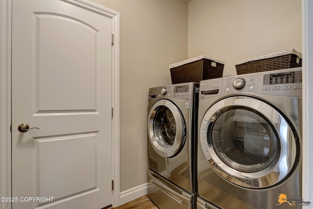 washroom with laundry area, washer and dryer, baseboards, and wood finished floors