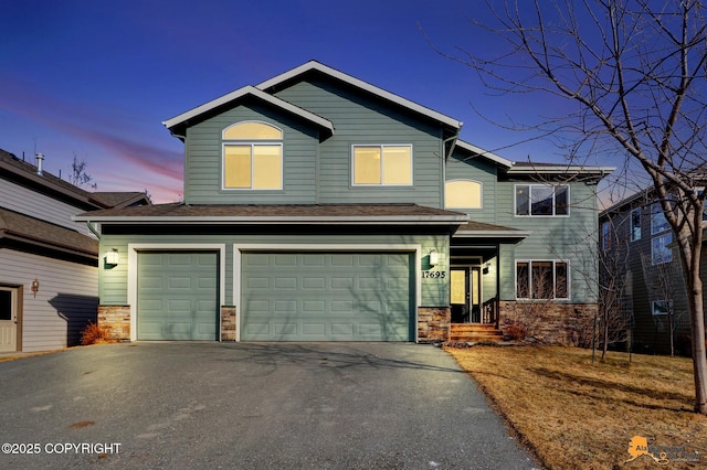 view of front of house featuring aphalt driveway, a garage, and stone siding