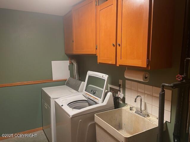 washroom with a sink, baseboards, cabinet space, and washer and clothes dryer