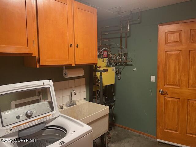 clothes washing area with cabinet space, washer / dryer, baseboards, and a sink