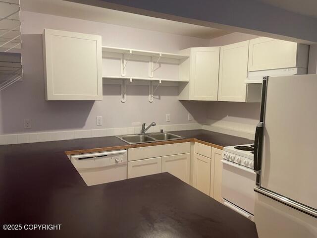 kitchen featuring dark countertops, a sink, white appliances, white cabinetry, and open shelves