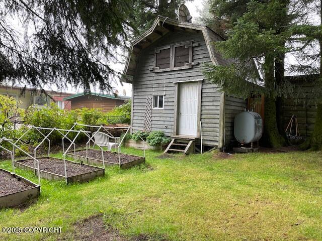 back of property with entry steps, heating fuel, a vegetable garden, and a yard