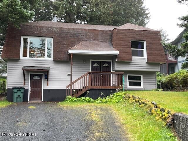 view of front of property featuring roof with shingles and a front lawn