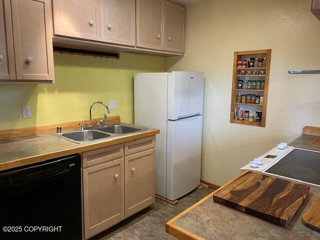 kitchen featuring dishwasher, freestanding refrigerator, and a sink