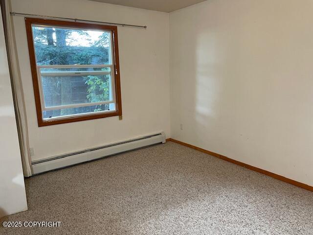 unfurnished room with a baseboard heating unit and baseboards