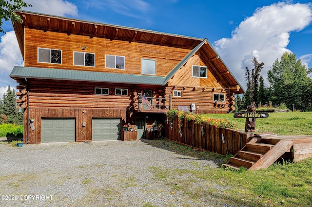 log-style house featuring log exterior, metal roof, driveway, and a garage