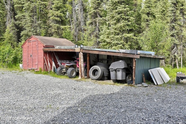 view of pole building featuring a view of trees and a carport