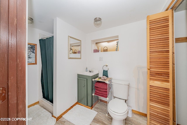 bathroom featuring curtained shower, toilet, vanity, and baseboards