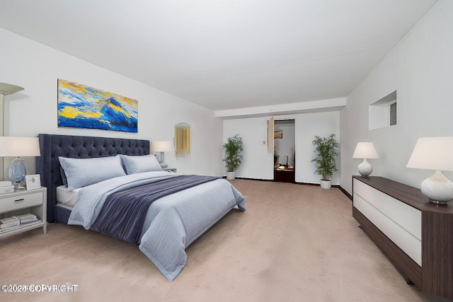 bedroom with arched walkways, light colored carpet, and baseboards