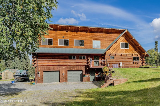 view of front facade with driveway, a front lawn, a garage, log exterior, and metal roof