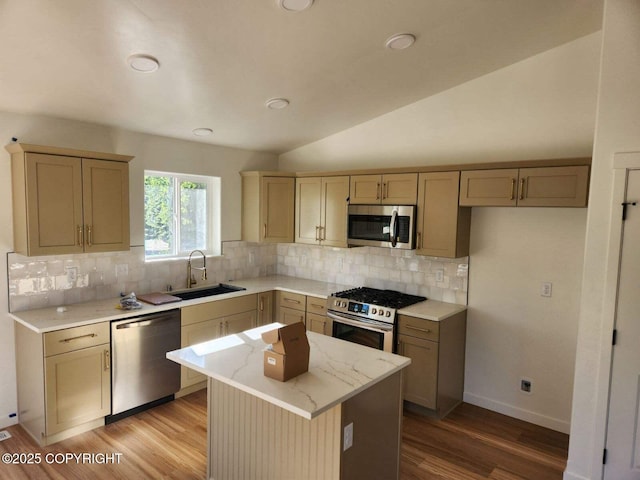 kitchen featuring lofted ceiling, light wood finished floors, appliances with stainless steel finishes, and a sink