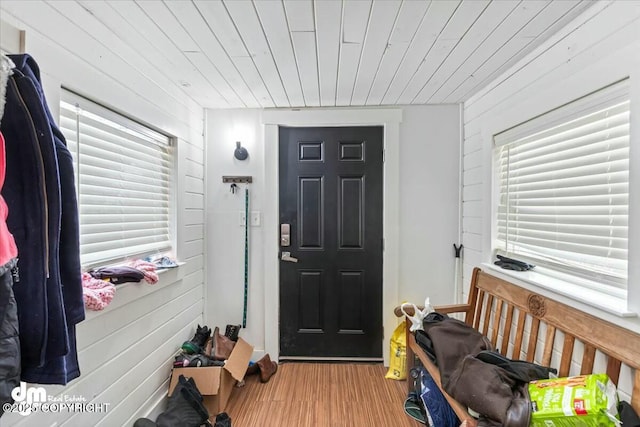 entryway with wood finished floors, wooden ceiling, and wood walls