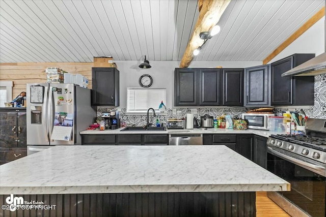 kitchen with vaulted ceiling with beams, a sink, decorative backsplash, extractor fan, and appliances with stainless steel finishes