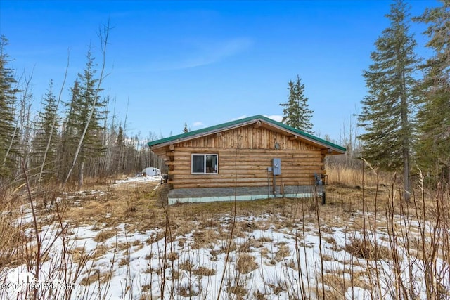 view of snow covered exterior with log siding