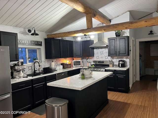 kitchen with dark cabinetry, a sink, stainless steel appliances, light countertops, and wall chimney exhaust hood