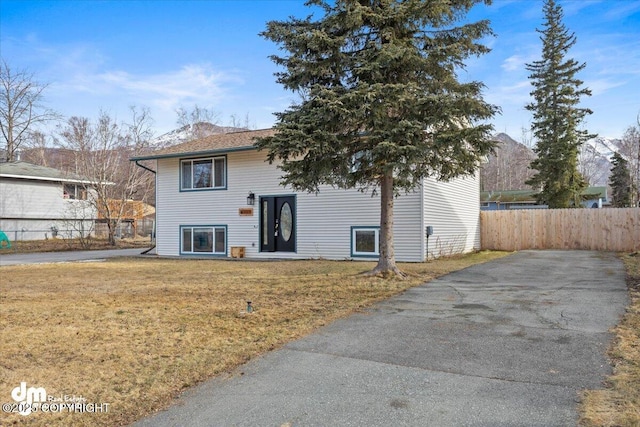 split foyer home with a front yard and fence